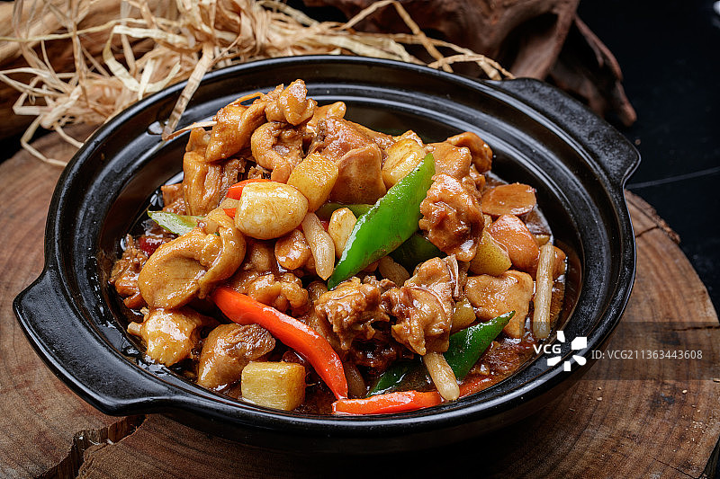 黑色砂锅装的砂锅蒜香鸡摆放在樟木砧板上图片素材