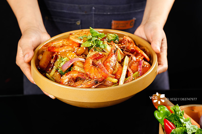 手里端着一盘麻辣香锅图片素材