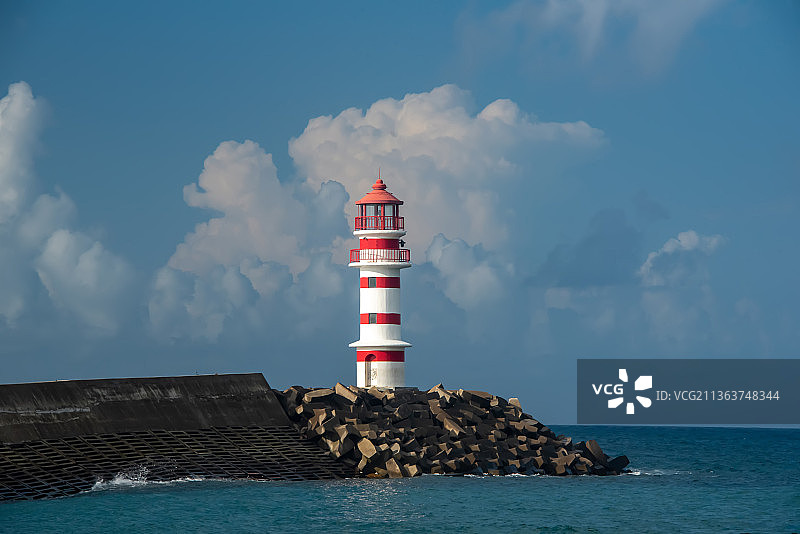 蓝天白云下，延伸到海洋中堤坝尽头，矗立着红白相间的灯塔图片素材