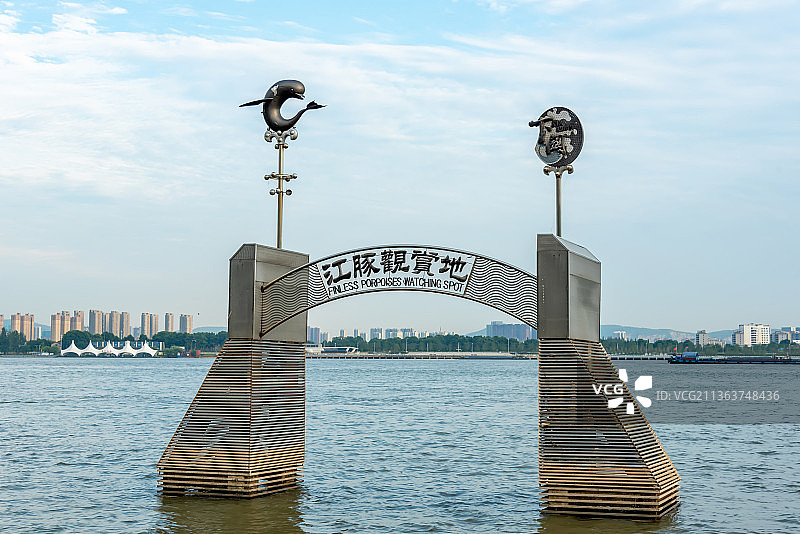 河中间矗立着一道金属几何规则排布的拱门，两边柱子上江豚的金属雕像，长江中的江豚观赏地标志图片素材