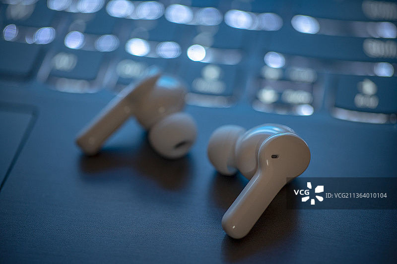 放置在电脑键盘上的蓝牙耳机图片素材