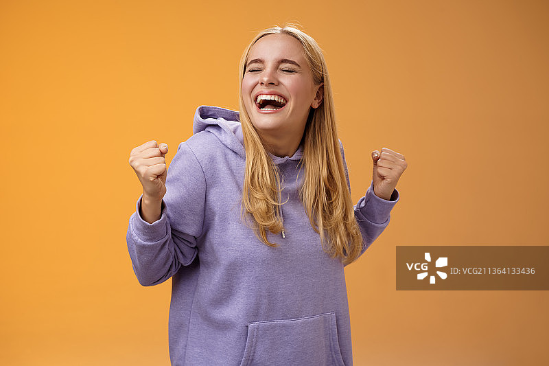 可爱的快乐的金发欧洲女孩穿着连帽衫欢呼雀跃图片素材