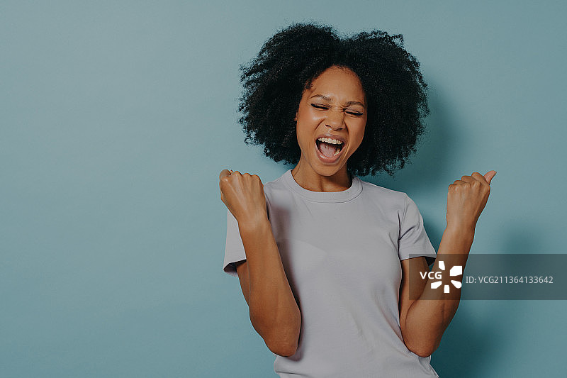 在蓝色工作室背景下穿着休闲服装的非裔美国女孩图片素材