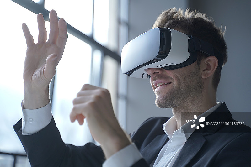 男员工穿着正式西装，兴奋地体验VR头显图片素材