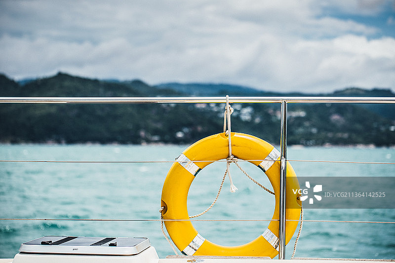 悬挂在船上的黄色救生圈特写，海洋背景图片素材