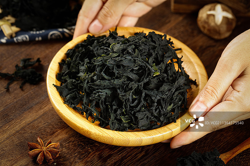 手里端着一盘无梗裙带菜图片素材