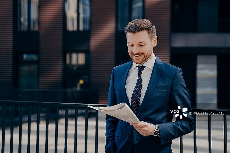 在户外阅读报纸的年轻富有进取心的商人图片素材