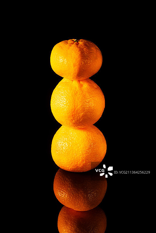 新鲜橘子金字塔，黑色背景下的橘子特写图片素材