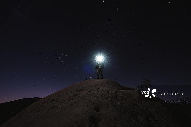 闪光灯，夜晚站在山上的男人仰视天空图片素材