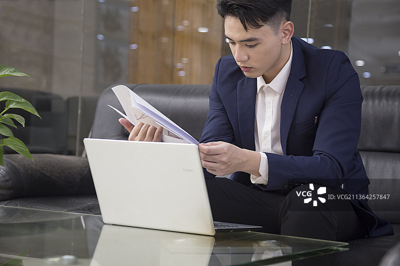 东方男性白领正在沙发前办公图片素材