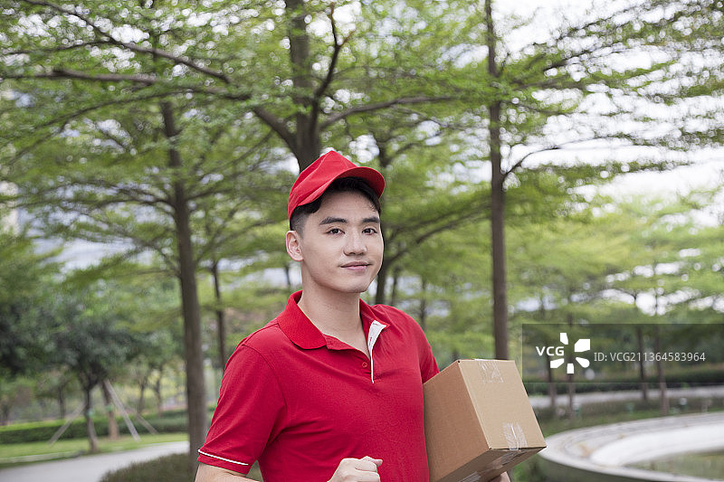 户外一名穿红色制服的男性快递员图片素材