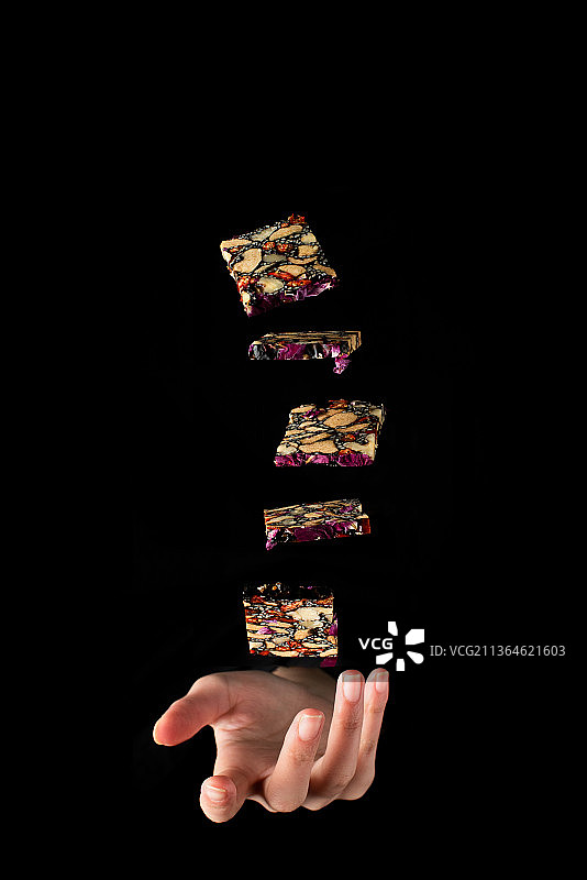 黑色背景下用手抛在空中的阿胶图片素材