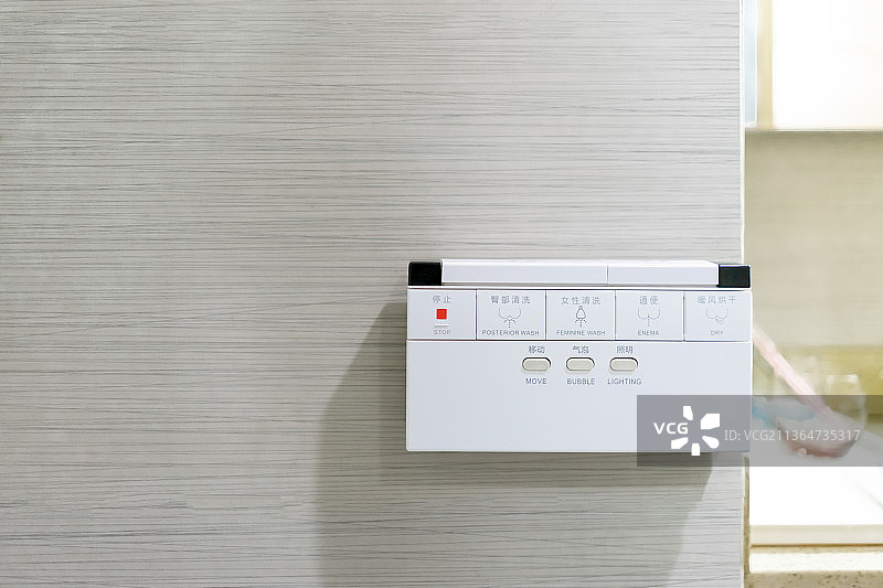 中国家庭室内装修设计，厕所里的智能水洗马桶和悬挂在墙壁上的操作按键面板图片素材