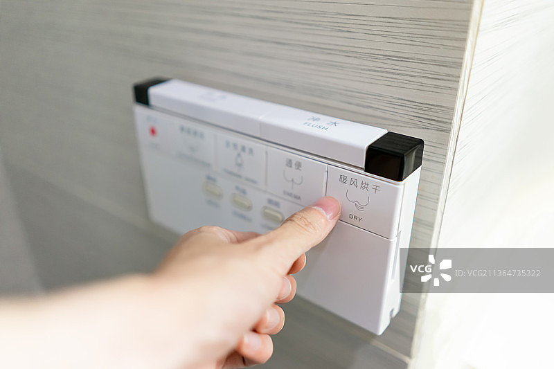 中国家庭室内装修设计，厕所里的智能水洗马桶和悬挂在墙壁上的操作按键面板图片素材