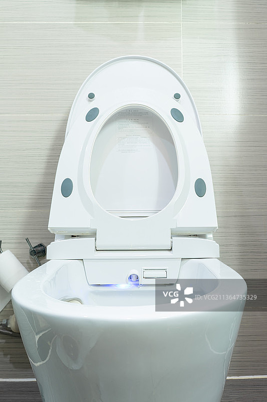 中国家庭室内装修设计，厕所里的智能水洗马桶和悬挂在墙壁上的操作按键面板图片素材