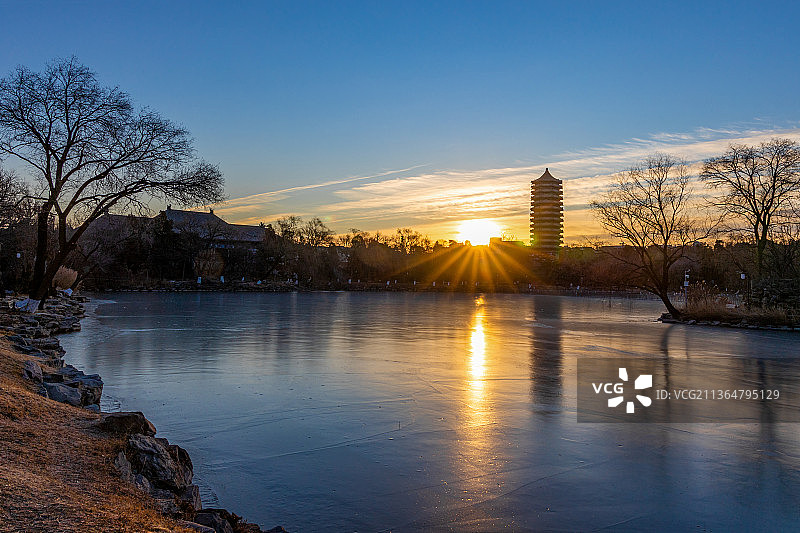 冬天朝阳光芒下的北京大学博雅塔与结冰的未名湖图片素材