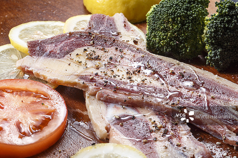 搭配柠檬西红柿西蓝花的澳洲牛仔骨摆放在木砧板上图片素材