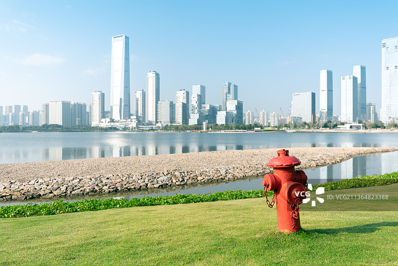 草坪上的一个消防栓和城市建筑背景图片素材