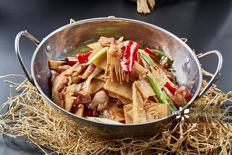黑色背景上的锅仔香辣腊肉煲鲜笋图片素材