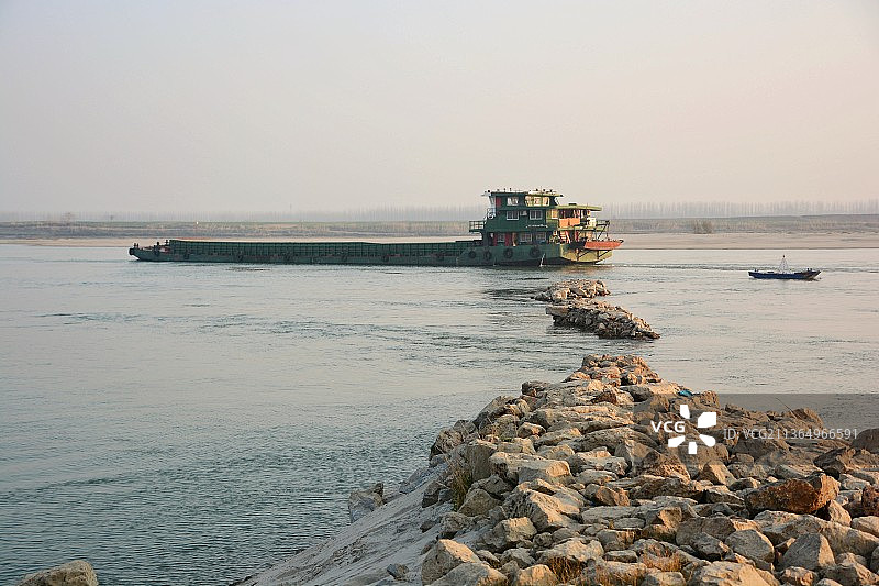 河滩上的石头和一艘行驶的货船图片素材