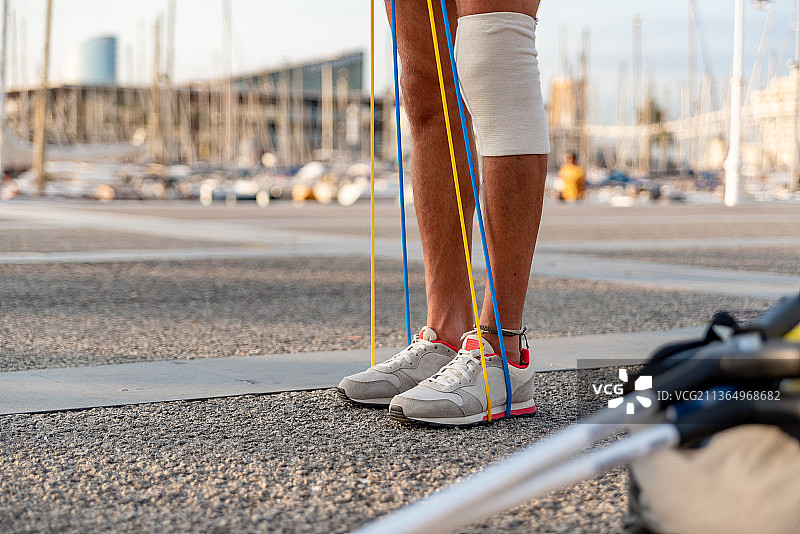 在户外锻炼的匿名年轻人，女人在路上系鞋带的下半身图片素材