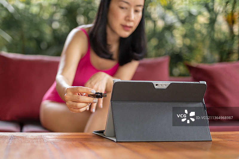 在泰国，穿着泳衣的女人将闪存盘插入笔记本电脑图片素材