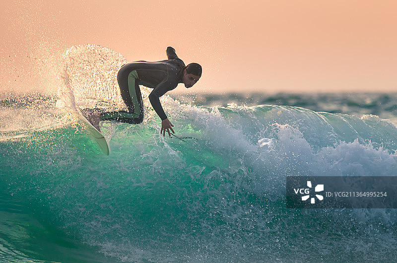 日落时分，年轻男人在海中冲浪图片素材