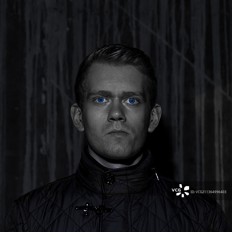 走出黑暗，靠墙的年轻男人肖像图片素材