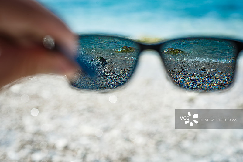 裁剪过的手在海滩上拿着太阳镜图片素材