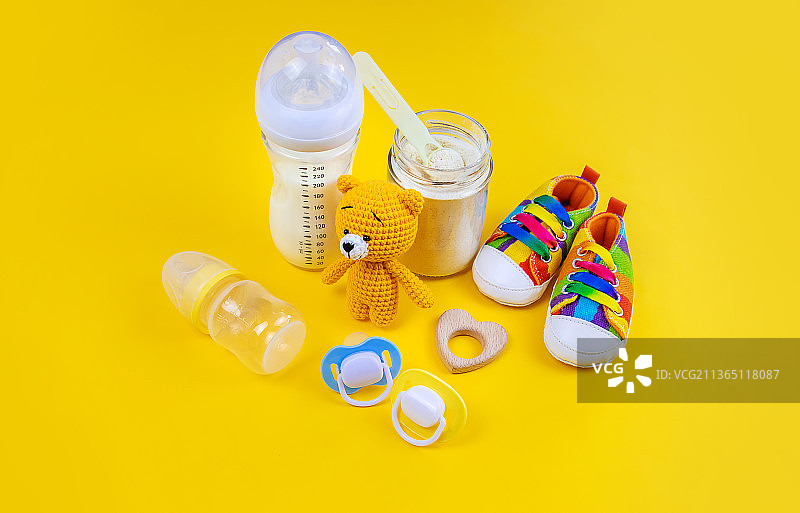 黄色背景上的婴儿奶及配件选择性聚焦图片素材