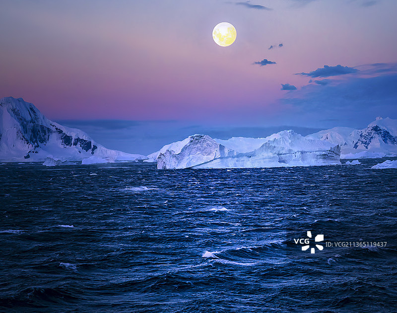 南极洲上空的满月，日落时分雪山映衬下的壮丽海景，南极洲图片素材