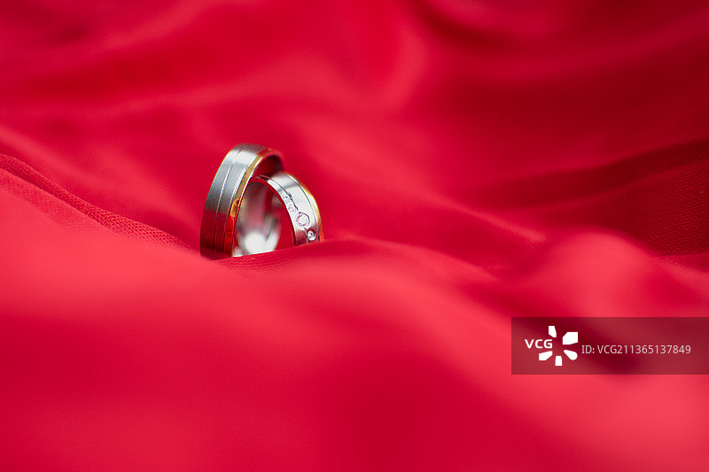 情人节贺卡：红色纺织品上的结婚戒指特写图片素材