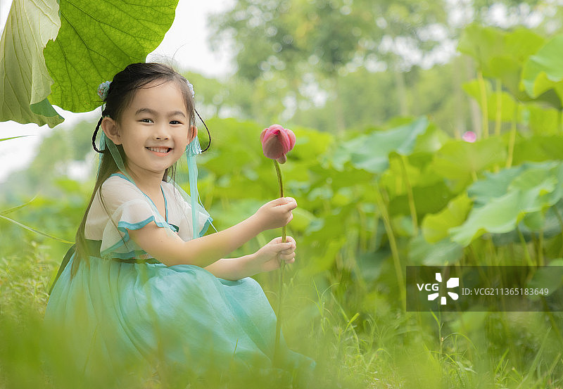 荷塘边手拿荷花穿汉服的看镜头笑的小女孩图片素材