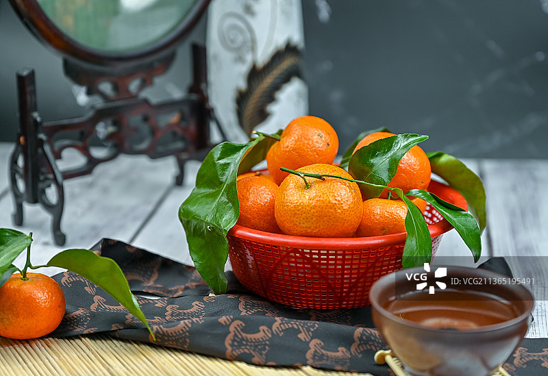 室内桌子上一筐带绿叶的桔子图片素材