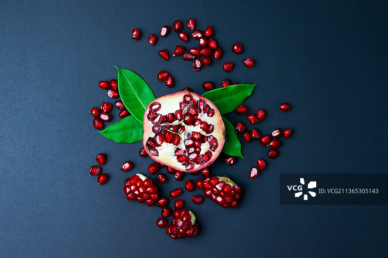 黑色背景上分离的新鲜石榴与绿叶图片素材