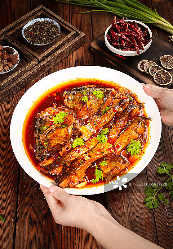 手里端着一盘香辣啤酒鱼图片素材
