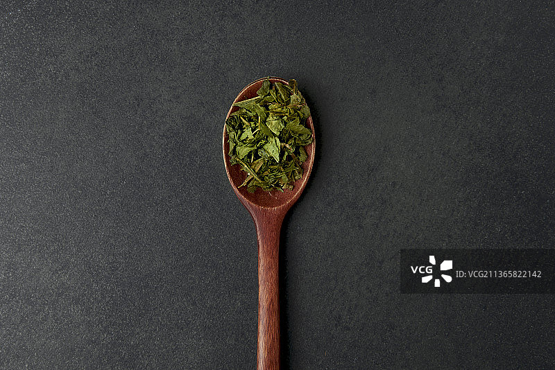 黑色背景木勺上的抹茶茶叶图片素材