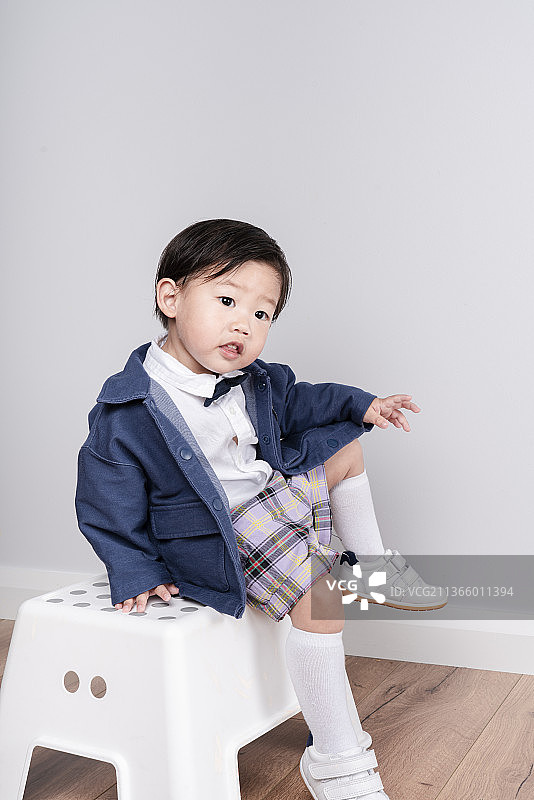坐在白凳子上摆造型的牛仔小男孩图片素材