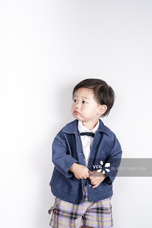 站在白墙前穿新衣服的可爱小男孩图片素材