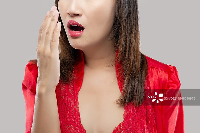 年轻女子对着灰色背景检查呼吸的特写镜头图片素材