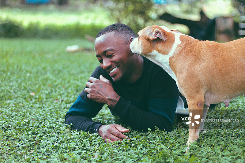 年轻的黑人男子和小猎犬玩耍图片素材