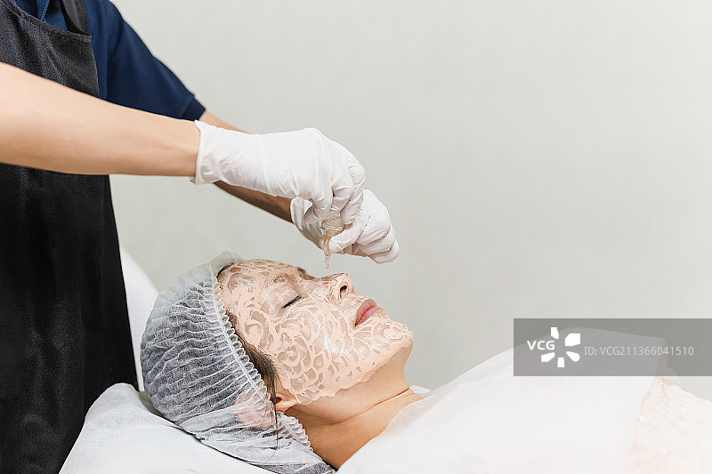 在泰国，亚裔女人用滴管精油做面部SPA护理图片素材