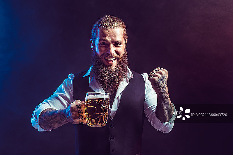 快乐的络腮胡男子拿着一杯生啤酒图片素材