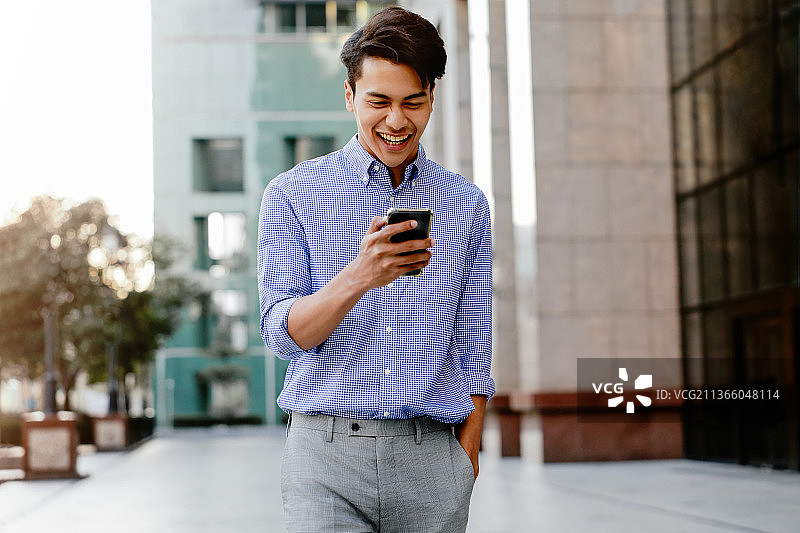 在泰国使用手机的快乐年轻商人肖像图片素材