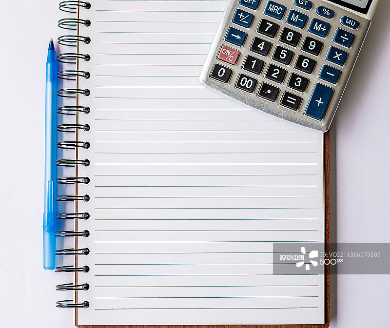 放置在桌子上的带计算器和笔的空白螺旋笔记本图片素材