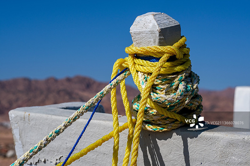 最美丽的色彩：系在系缆桩上的绳索特写，背景是晴朗的蓝天图片素材