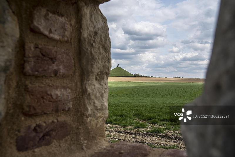 从滑铁卢战役战场和狮子山，透过乌古蒙城堡花园墙上的漏洞，英国军队在1815年6月18日的滑铁卢战役中面对拿破仑军队的农舍图片素材