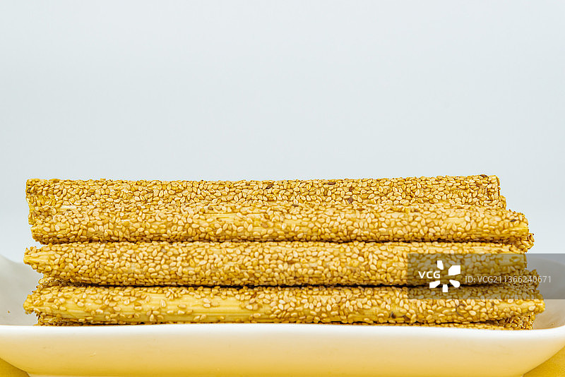 摆放在白色瓷盘里的芝麻麦芽糖糖瓜图片素材