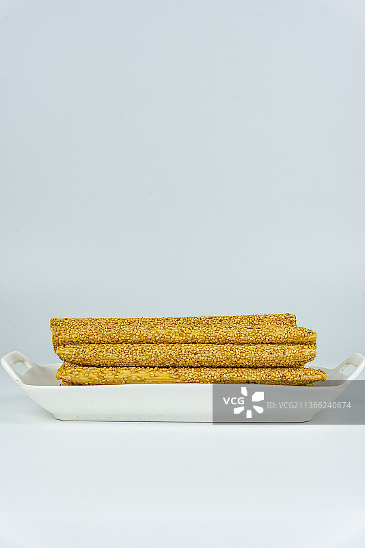 摆放在白色瓷盘里的芝麻麦芽糖糖瓜图片素材