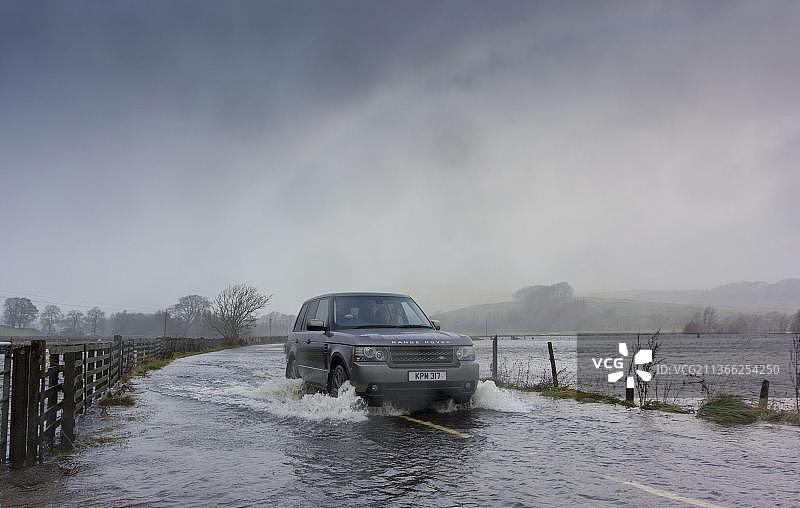 路虎汽车在暴雨淹没的道路上行驶，英国北约克郡图片素材